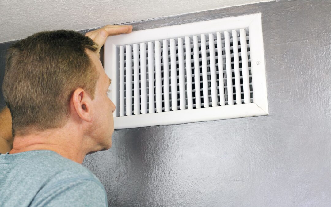 Homeowner inspects a vent before attempting DIY air duct cleaning