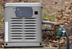 Home generator installation - gray standby unit with green indicator light and gas connections