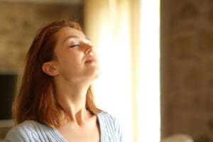 HVAC Services Lynchburg VA woman breathing clean fresh air in naturally lit home interior